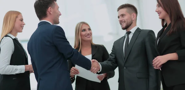 Equipo de negocios de pie en una oficina y estrechando las manos . — Foto de Stock