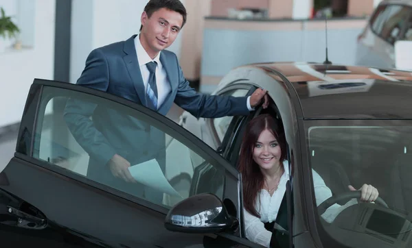 Jovencita eligiendo coche nuevo para comprar en la tienda de concesionarios — Foto de Stock