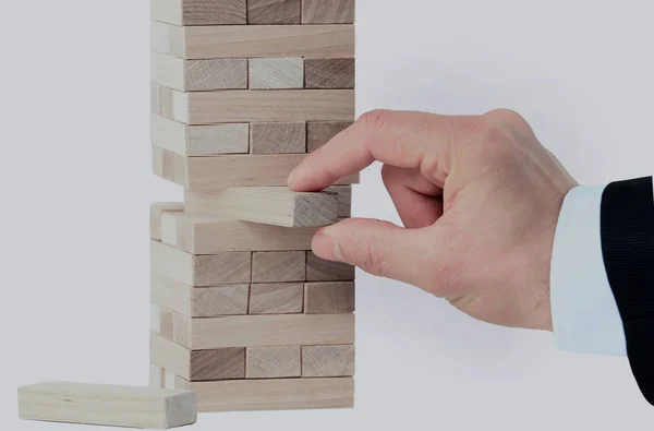 Башня из деревянных блоков и человек руки взять один блок — стоковое фото