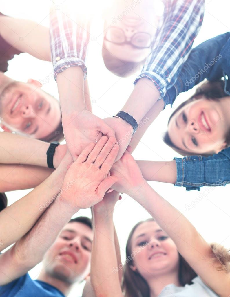 group of smiling teenagers with hands on top of each other