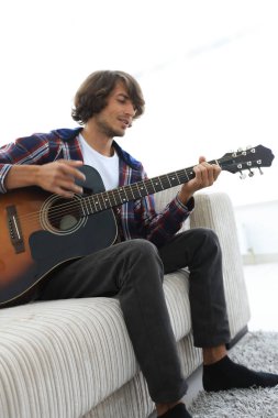 adam bir şarkı söyler ve kanepede oturan gitar çalar.