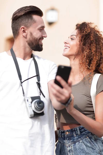Улыбающаяся пара, использующая смартфон вместе в городе — стоковое фото