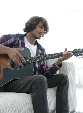 adam bir şarkı söyler ve kanepede oturan gitar çalar.