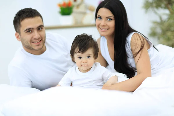 Familia alegre divirtiéndose juntos acostados en una cama —  Fotos de Stock