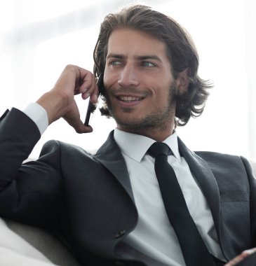 iş adamı rahat bir sandalyede otururken Smartphone'da konuşuyor.