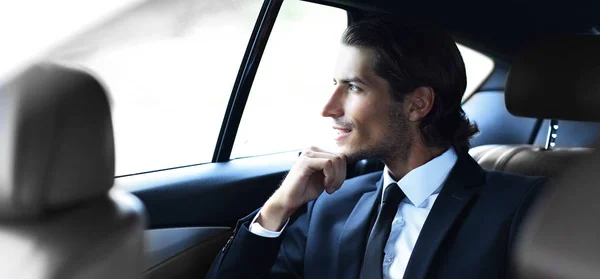 Successful man sitting in the back seat of a car — Stock Photo, Image