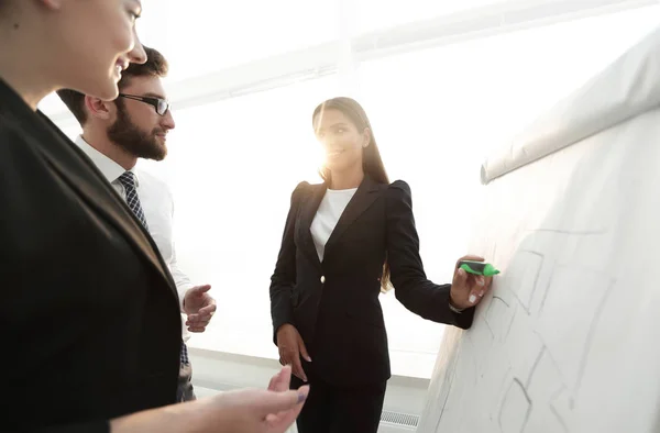 Business woman pointing with a marker on the flipchart — Stock Photo, Image