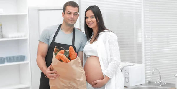 Husband and pregnant wife holding a package of baguettes — Stock Photo, Image