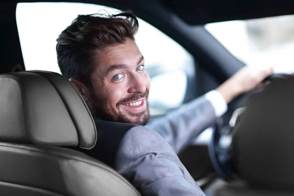 Rear view, young man driving his car, looking at camera — Stock Photo, Image