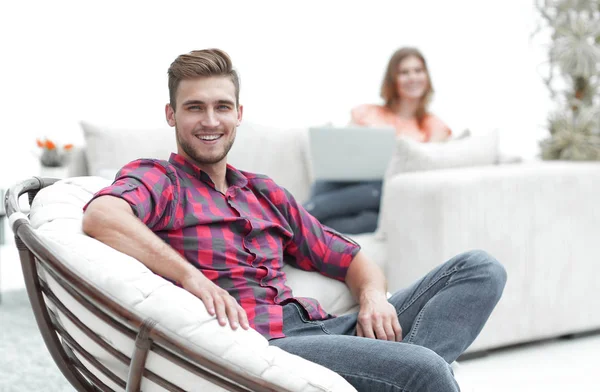 Sonriente joven macho sentado en una silla grande — Foto de Stock