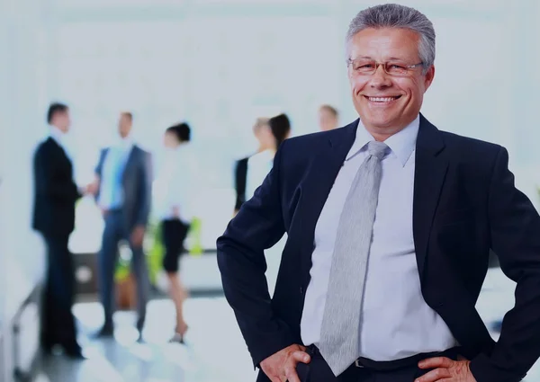 Успешный бизнесмен, стоящий со своим персоналом на заднем плане в офисе . — стоковое фото