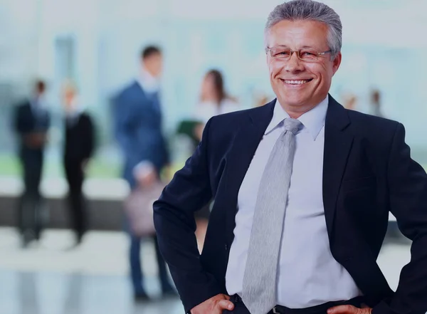 Erfolgreicher Geschäftsmann steht mit seinen Mitarbeitern im Hintergrund im Büro. — Stockfoto