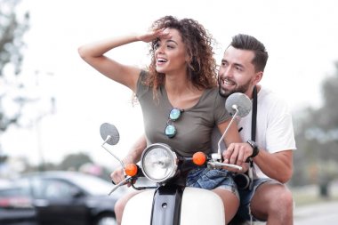 Güzel genç bir çift bir scooter sürme sırasında gülümsüyor