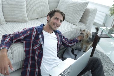 başarılı adam kanepede yakın katta oturan hayvanını okşayarak