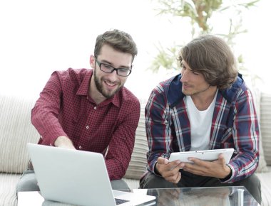 dizüstü ve tablet kanepede oturan çalışan iki genç adam