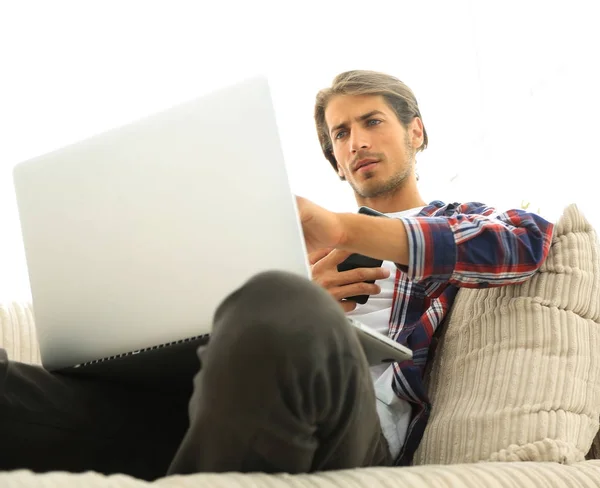Photo young guy with smartphone sitting in a chair. on a blurry background — Stock Photo, Image