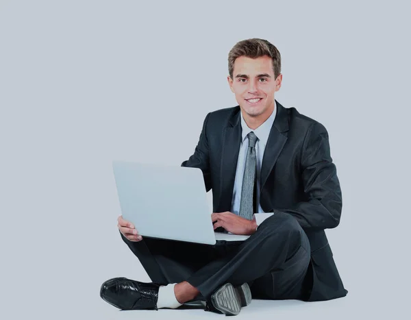 Jovem empresário isolado sentado usando um laptop — Fotografia de Stock