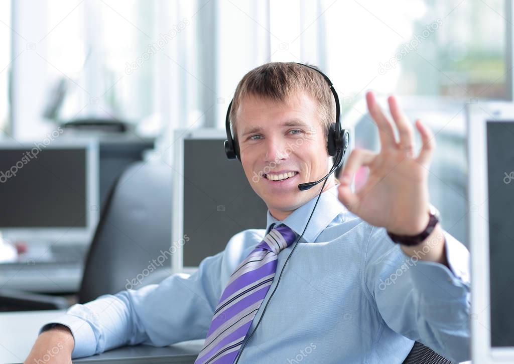 Happy young business man in headset working on computer.