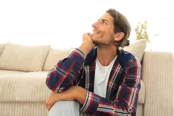 Close-up van een gelukkig man zittend op het tapijt in een nieuw appartement. — Stockfoto