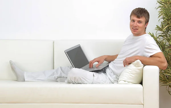 Πολύ εστιασμένη νεαρός άνδρας που χρησιμοποιούν φορητό υπολογιστή ενώ κάθεστε άνετα. — Φωτογραφία Αρχείου