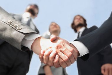 İş ortaklarının el sıkışması ön planda.