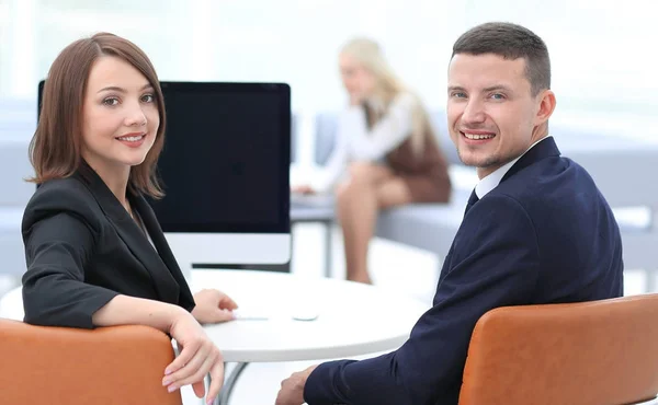 Membros da equipe de negócios sentados na mesa e olhando para a câmera — Fotografia de Stock