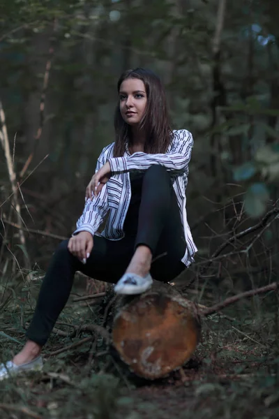 Hermosa joven sentada en un tronco — Foto de Stock