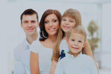 ön planda gülümseyen oğluyla mutlu bir aile görüntüsü.