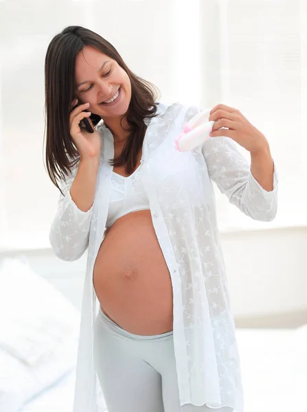 Mujer embarazada sonriente hablando en su smartphone . — Foto de Stock