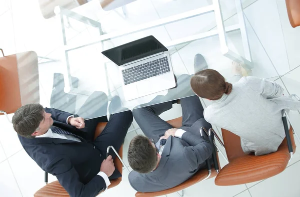 Three business people, meeting around a boardroom table