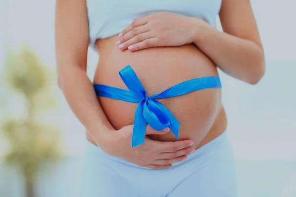 Mulher de mãos dadas em seu bebê colisão, amarrado com um arco azul . — Fotografia de Stock