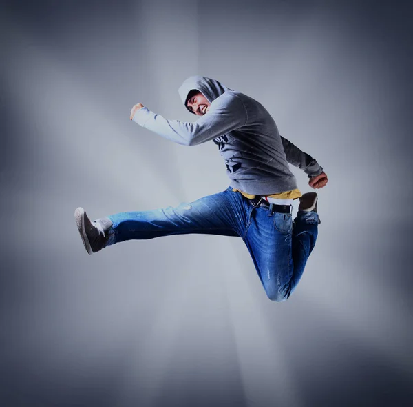 Portret van een jonge man springen in de lucht tegen lichte achtergrond. — Stockfoto