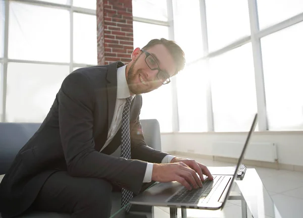 Jeune homme d'affaires utilisant un ordinateur portable et souriant — Photo