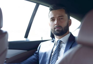 arabanın arka koltuğunda oturan yakışıklı sakallı işadamı