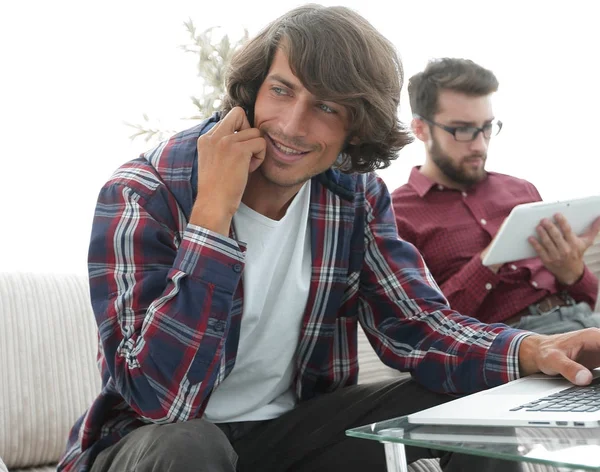 Dois caras sentados no sofá, conversando no smartphone e se comunicando na Internet . — Fotografia de Stock