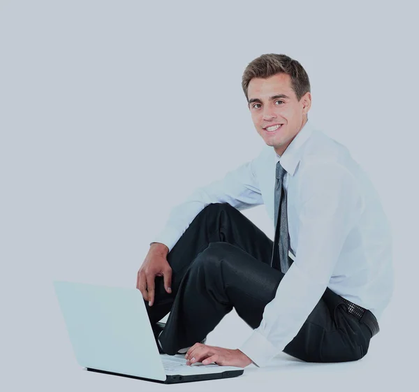 Na białym tle siedzi młody biznesmen za pomocą laptopa. — Zdjęcie stockowe