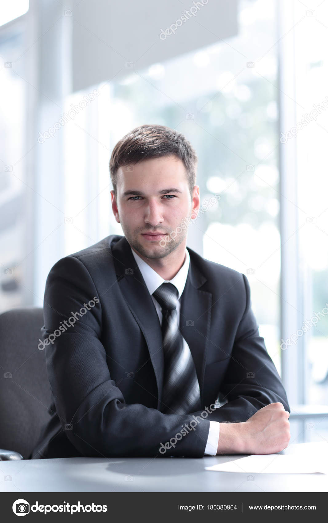 Portrait Of Confident Businessman Sitting Behind A Desk Stock