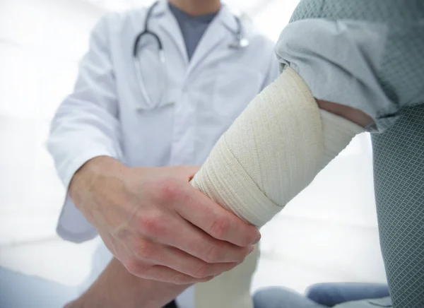 Orthopédiste appliquant un bandage sur les patients main dans la main en clinique — Photo