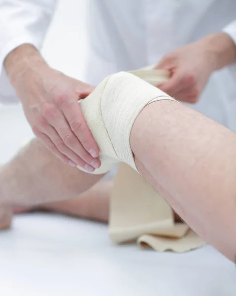 Arzt behandelt Wunde am Bein des Patienten im Klinikzimmer — Stockfoto