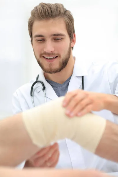 Traumatologista examinando a bandagem em seu joelho . — Fotografia de Stock