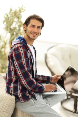 dizüstü bilgisayarda çalışan ve kameraya bakarak şık genç adam