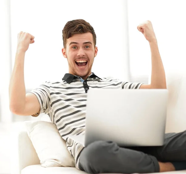 Hombre feliz con el ordenador portátil sentado en el sofá — Foto de Stock