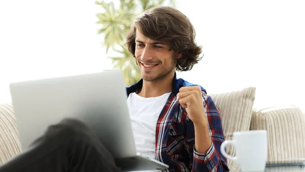 Очень счастливый парень с ноутбуком, сидящий за журнальным столиком . — стоковое фото