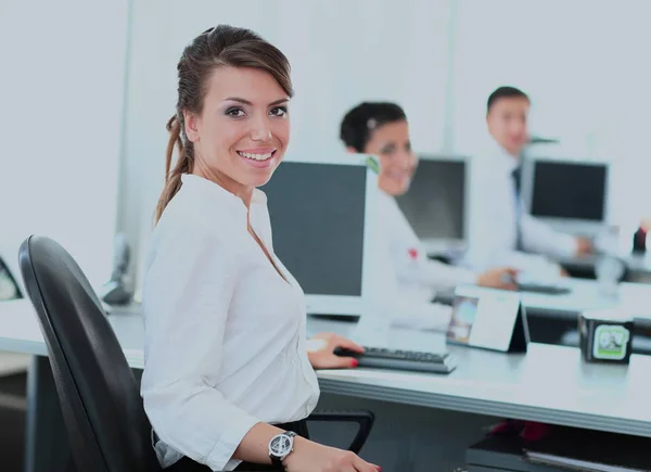 Feliz joven empresaria mirando atrás y sus colegas trabajando en la oficina . — Foto de Stock