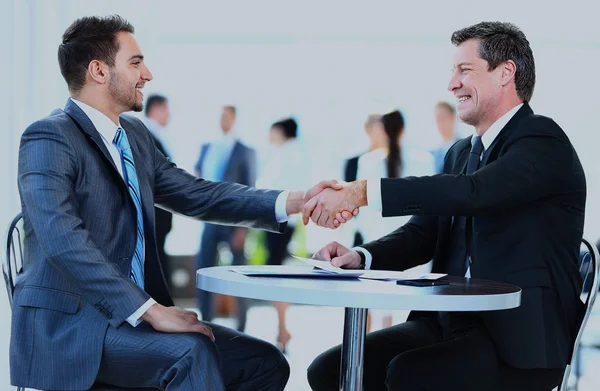 Compañeros de negocios sentados en una mesa y dándose la mano . —  Fotos de Stock