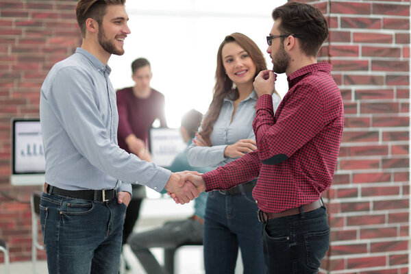 Smiling businessman shaking hands with colleague in office.