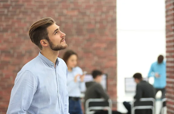 Joven hombre de negocios mirando hacia otro lado mientras trabaja en la oficina . — Foto de Stock