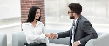 Yöneticisi ve müşteri ofis lobisinde otururken el sıkışma.