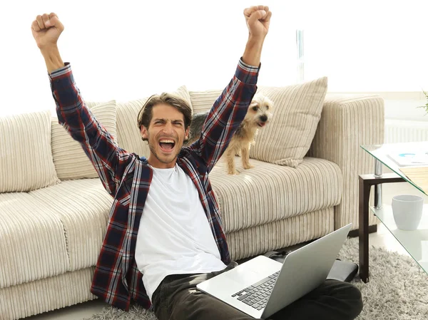 Счастливый молодой человек ликует со своей собакой, сидящей в гостиной — стоковое фото