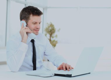 bilgisayar çalışma ve telefonda konuşurken işadamı.
